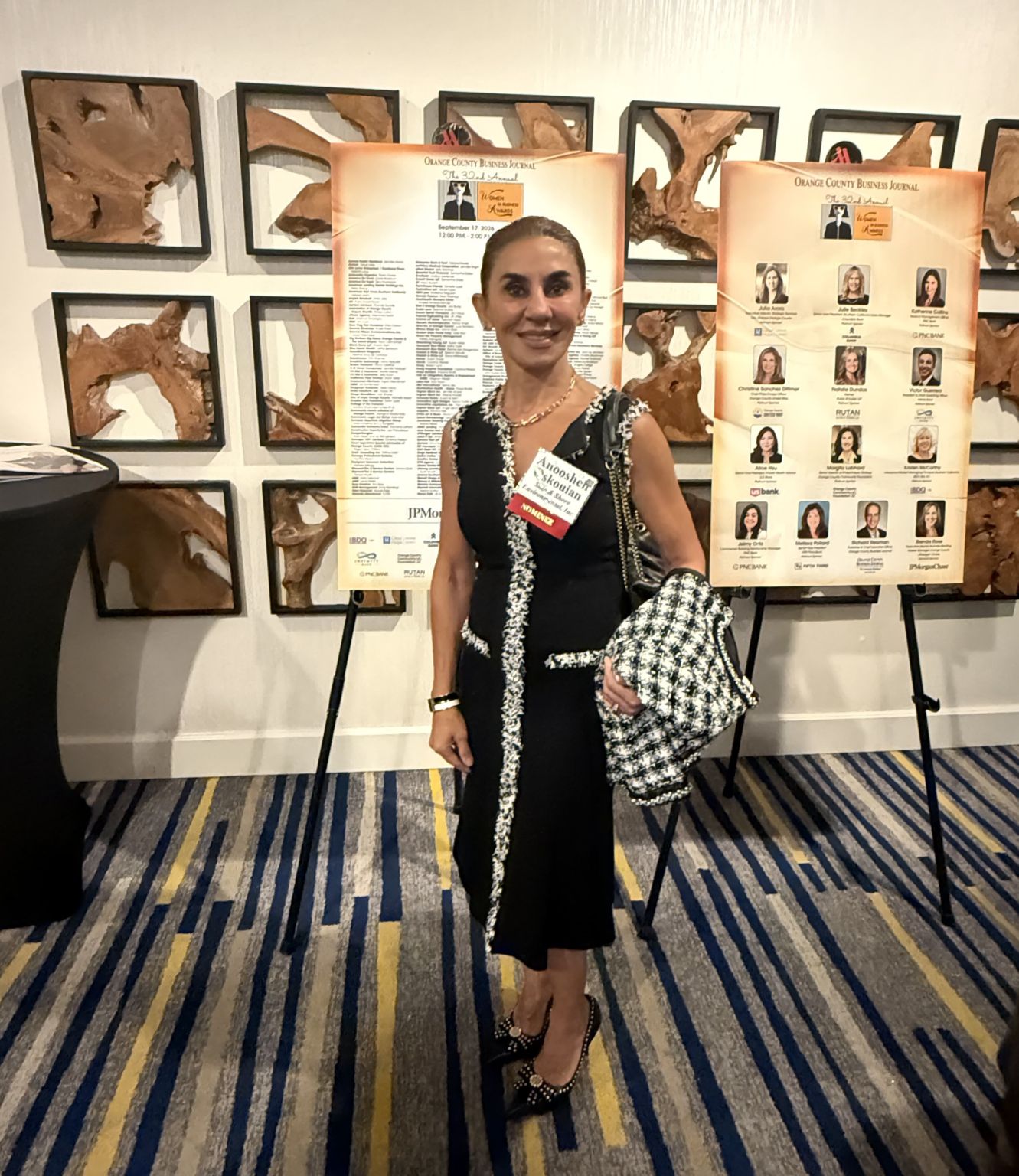 Anoosheh Mostafaei-Oskouian wearing a nominee badge beside the event’s nominee display boards